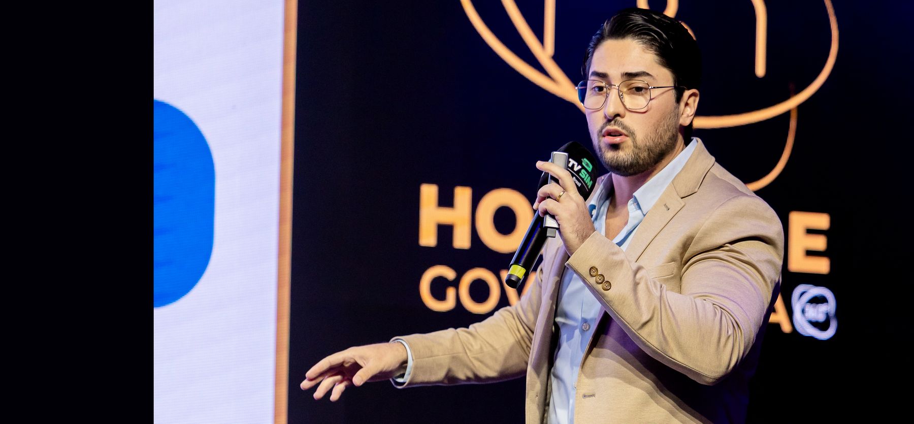 Yuri Reis no palco, de microfone na mão, conduzindo a Imersão Comercial